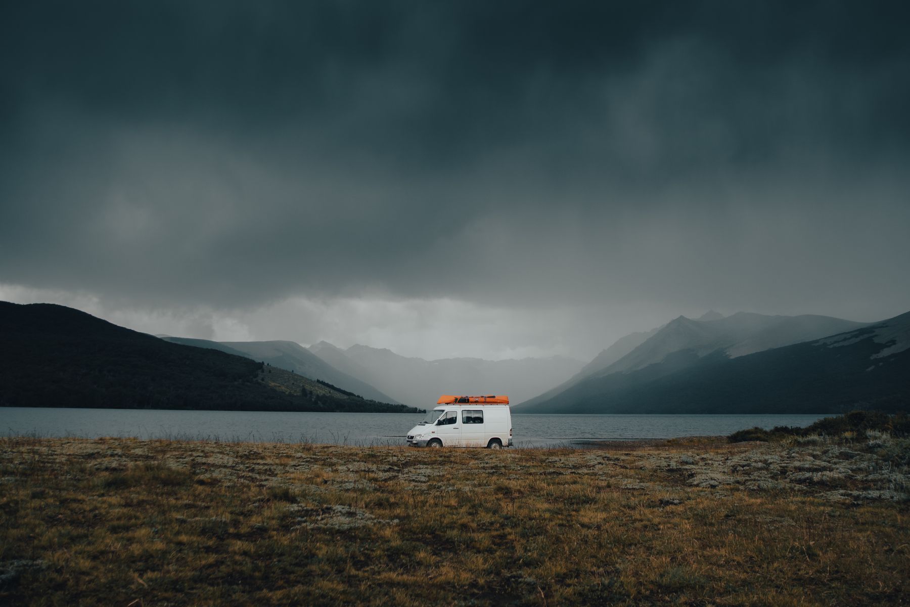 Camping-car blanc stationné au bord d'un lac montagneux au lever du jour