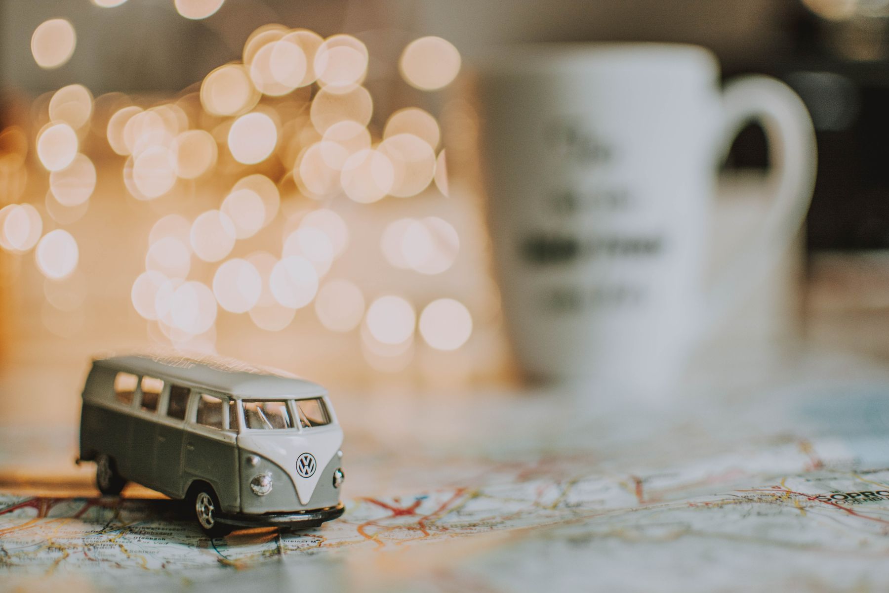 Petite automobile miniature blanche avec lumières dorées bokeh et tasse floue